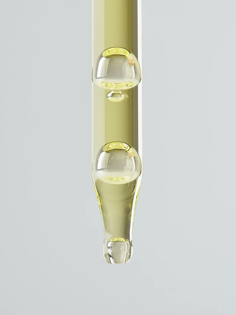 Glass dropper with LESSE Ritual Serum in a clear container on a light gray background