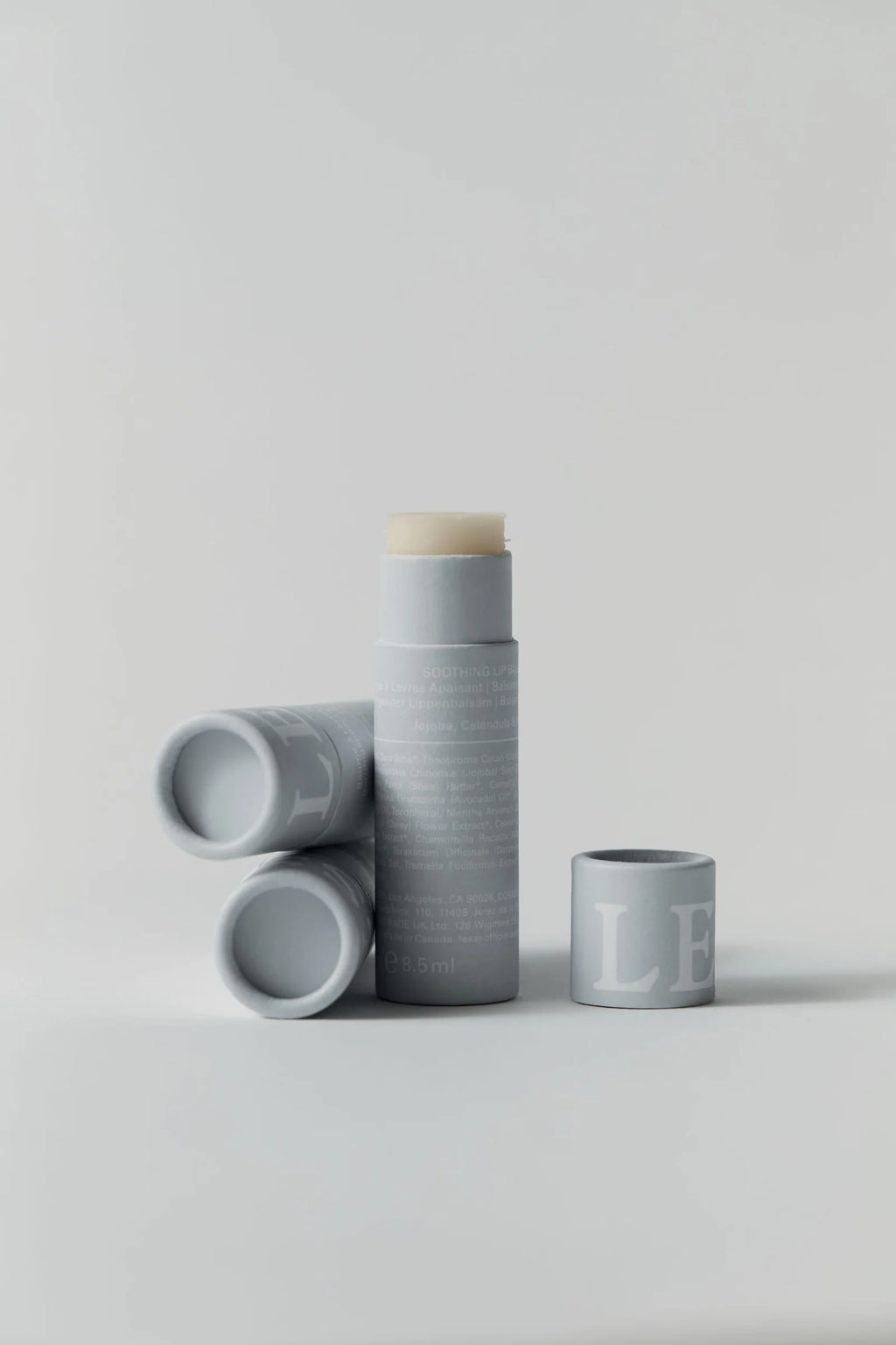 Set of LESSE Lip Balm containers with a white lid on a light gray background