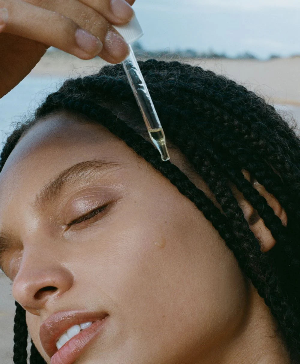 Person applying a dropper of LESSE to their face