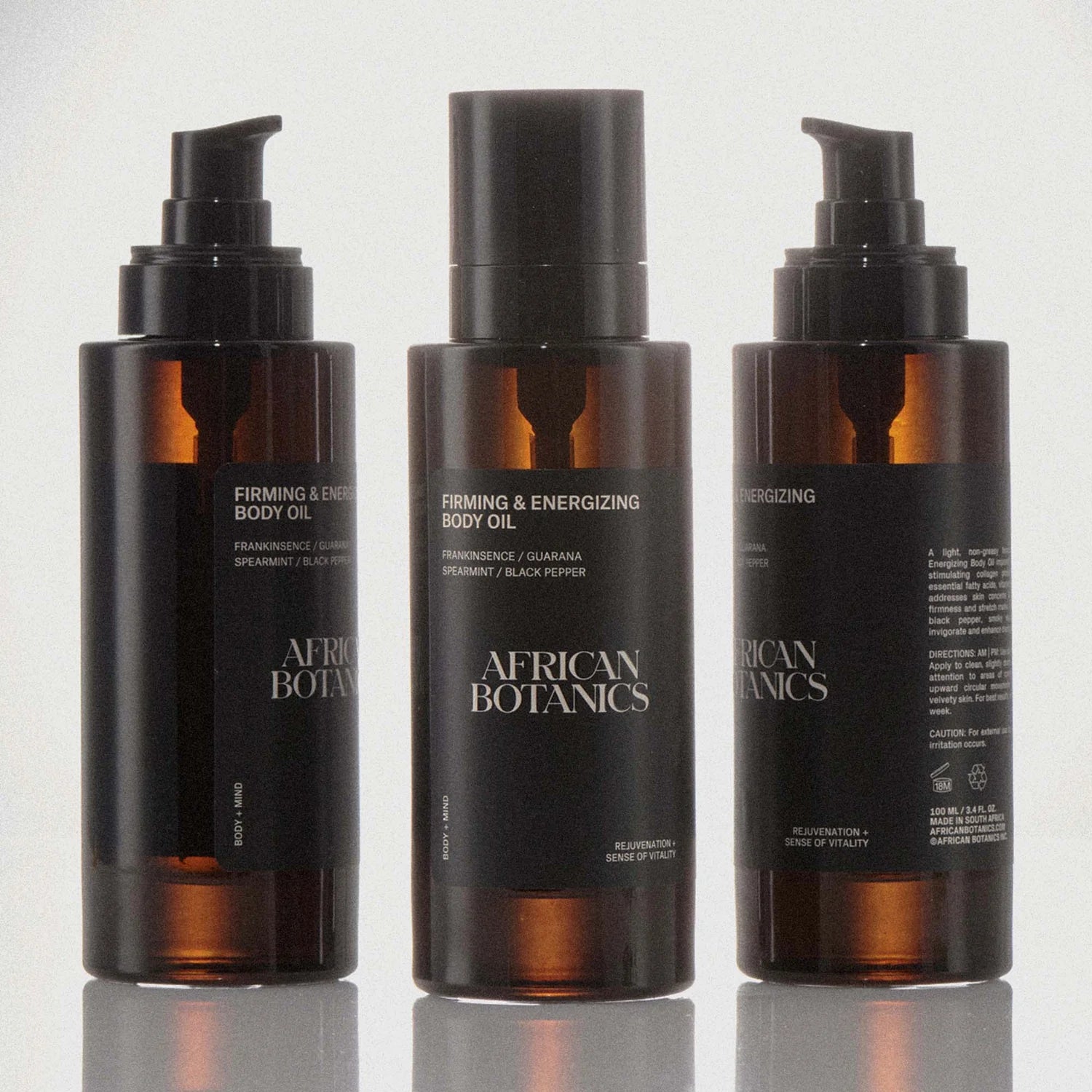 Three bottles of African Botanics Firming & Energizing Body Oil on a white background