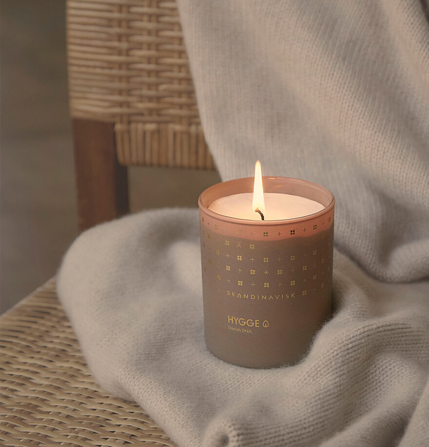 Candle in a decorative container labeled 'Brändinavala' on a textured surface with a blurred background
