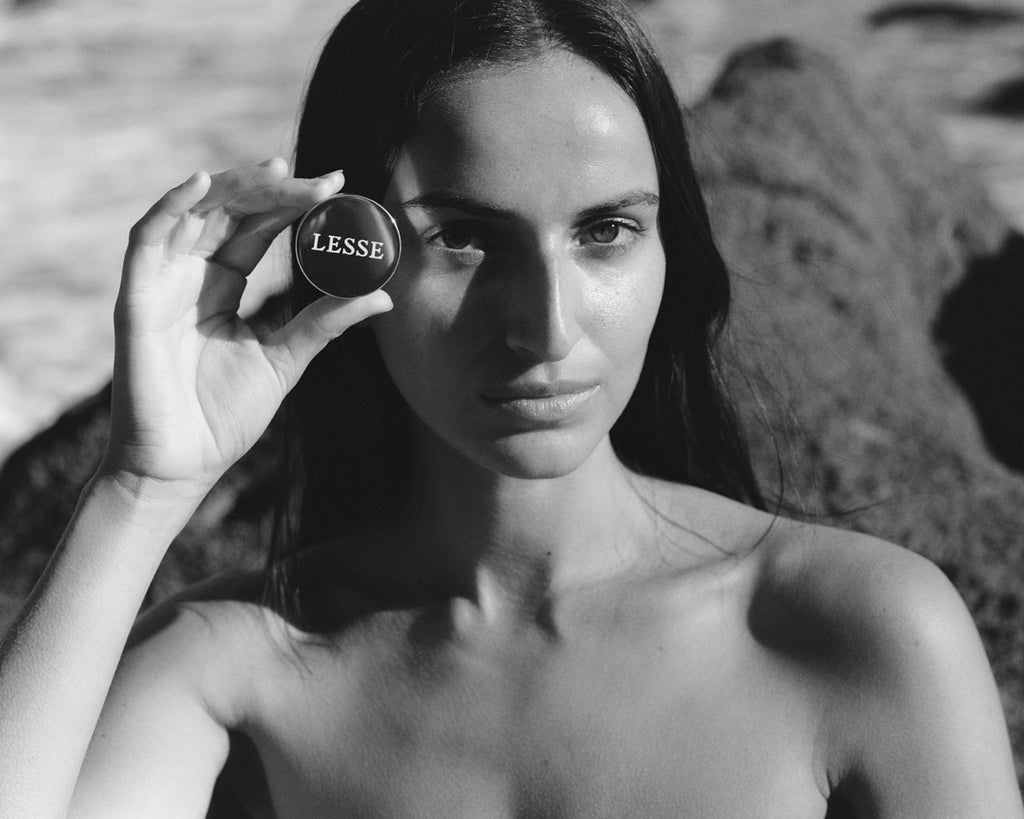 Woman holding a round object with 'LESSE' branding against a natural background