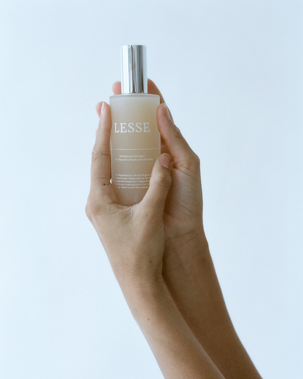 Hand holding a bottle of 'LESSE' against a light background