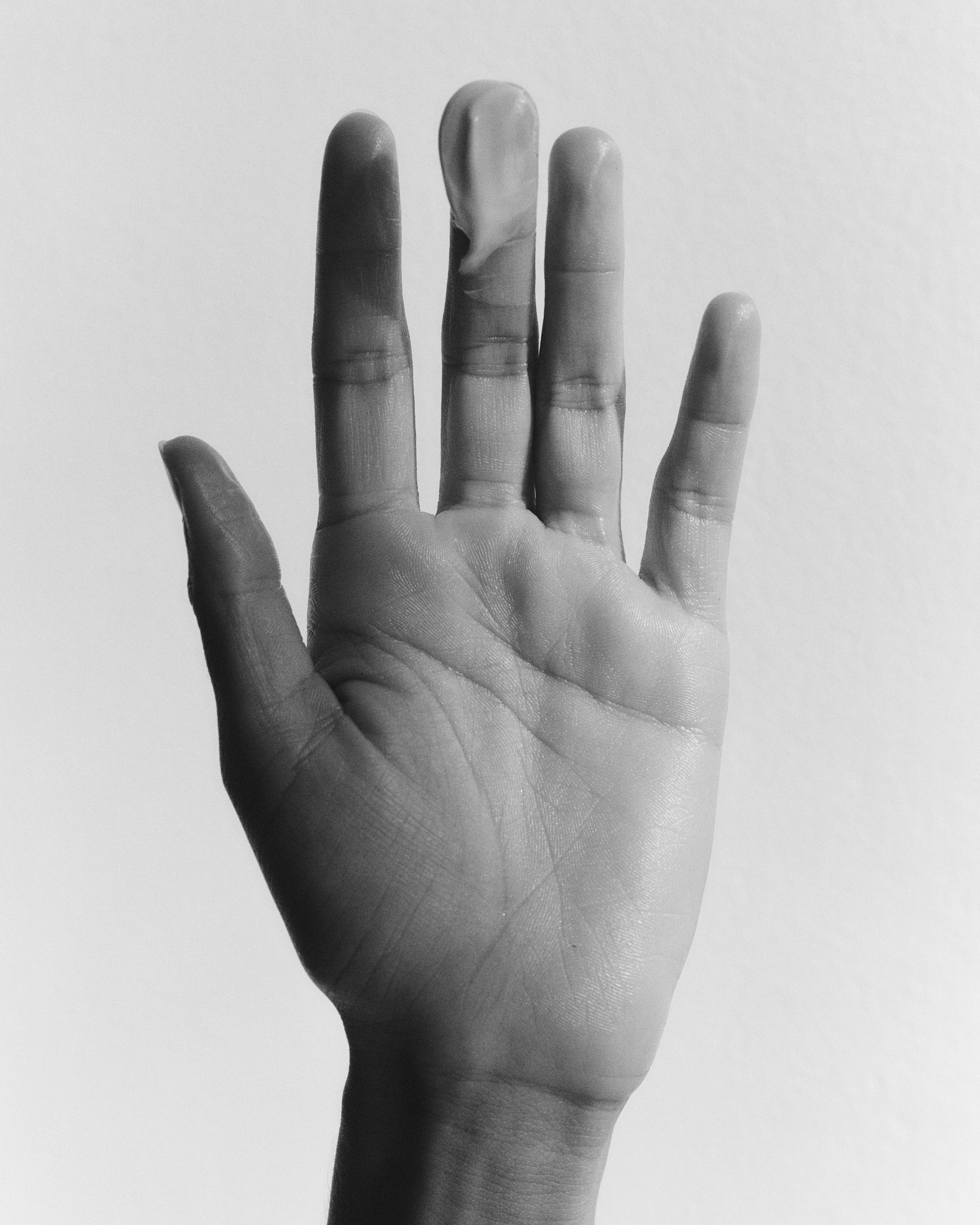 Black and white photograph of a hand with fingers extended on a light background