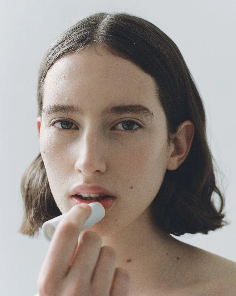 Woman applying lip balm on a white background