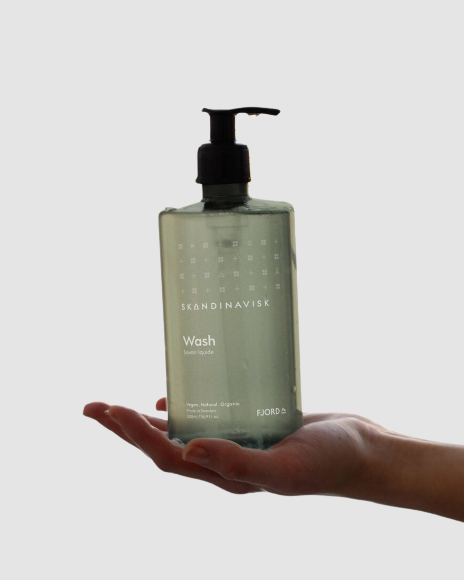 Hand holding a Skandinavisk bottle of Wash against a light gray background