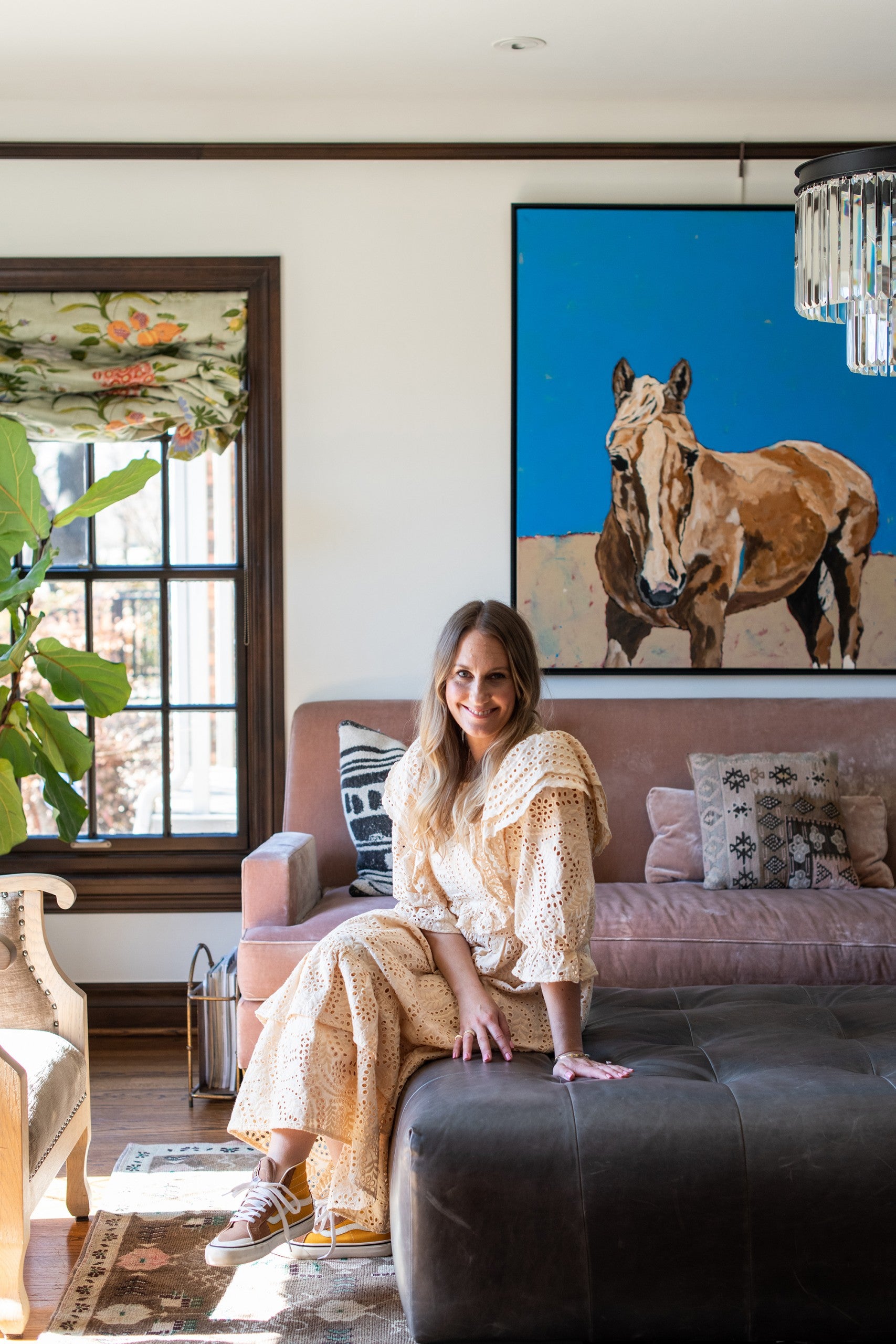 Andrea Ridley, udander founder sitting on a couch in a stylish living room with a horse painting on the wall.