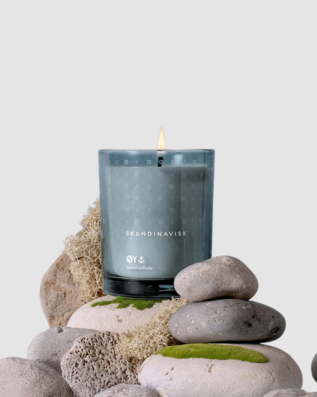 Skandinavisk candle on a stack of stones with a light gray background